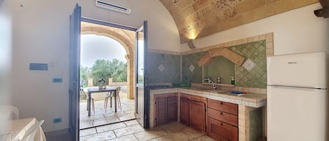 Una cocina con un arco abierto que da a un espacio exterior, un fregadero, una estufa y alacenas.