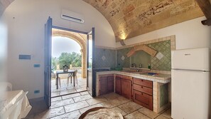 A kitchen with an open archway leading to an outdoor area, a sink, a stove, and cabinets. - Apartment 'Kambusa - Pozzo Pasulo - B' with Sea View, Wi-Fi and Air Conditioning (Morciano di Leuca)