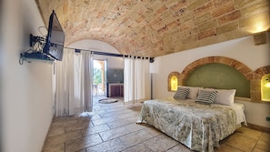 A bedroom with a bed, a television mounted on the wall, and a view of the outside through an open door. - Apartment 'Kambusa - Pozzo Pasulo - B' with Sea View, Wi-Fi and Air Conditioning (Morciano di Leuca)