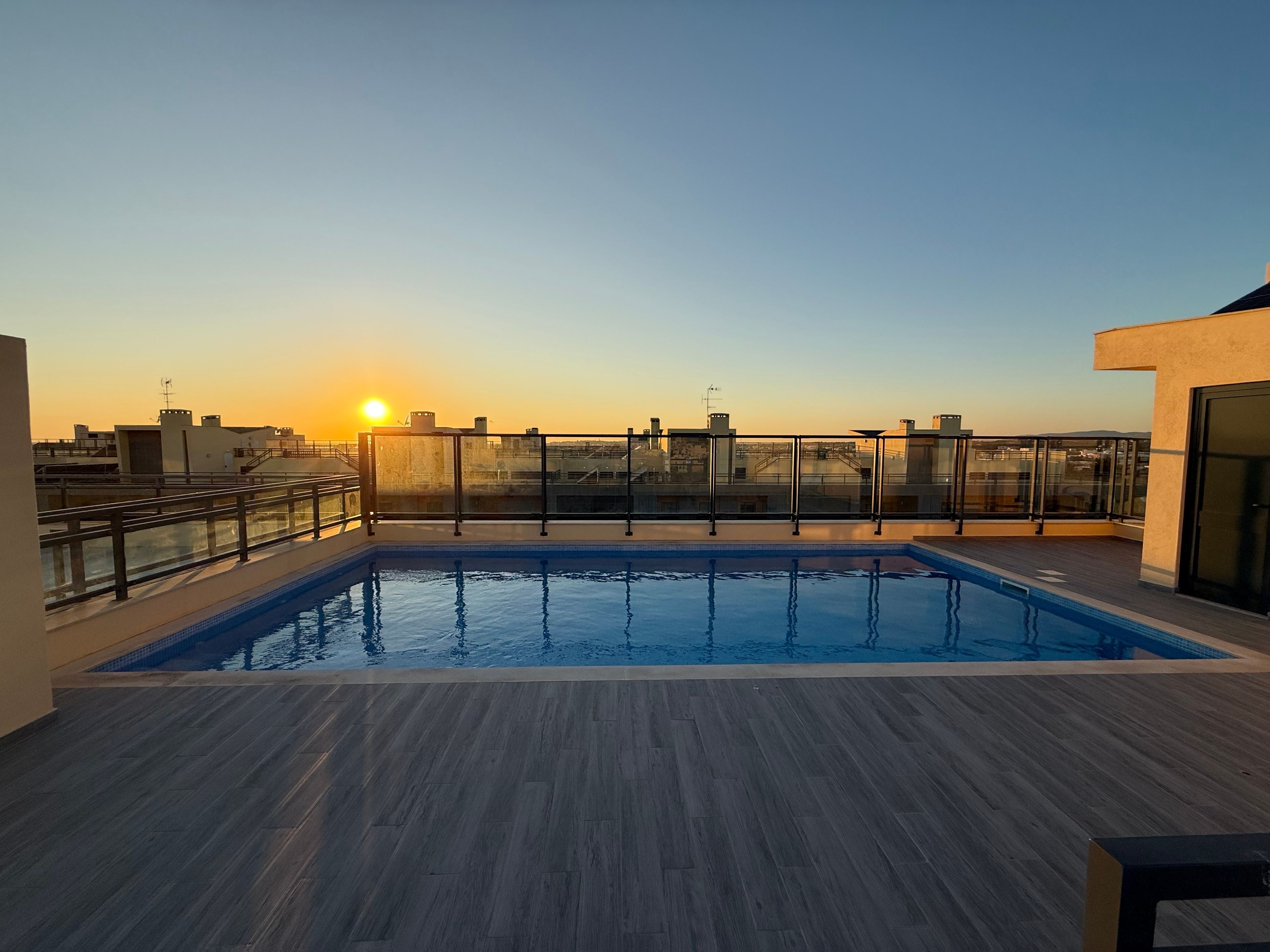 Ein Pool auf dem Dach mit Blick auf den Sonnenuntergang und die Skyline der Stadt.