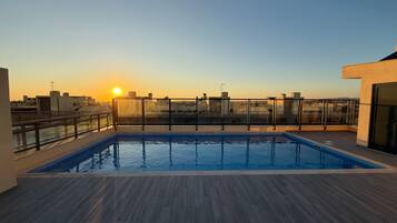 Ein Pool auf dem Dach mit Blick auf den Sonnenuntergang und die Skyline der Stadt.