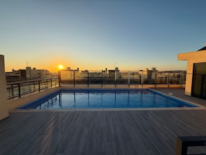 Ein Pool auf dem Dach mit Blick auf den Sonnenuntergang und die Skyline der Stadt.