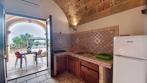A kitchen with a stone archway leading to a patio area, a sink, cabinets, and a refrigerator. - Apartment 'Kambusa - Pozzo Pasulo - C' with Sea View, Wi-Fi and Air Conditioning (Morciano di Leuca)