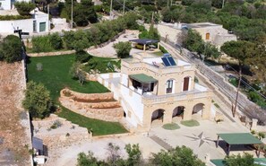 A building with a solar panel, a covered outdoor seating area, and a stone pathway. - Apartment 'Kambusa - Pozzo Pasulo - C' with Sea View, Wi-Fi and Air Conditioning (Morciano di Leuca)