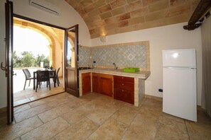 A kitchen with an open archway leading to a dining area, a refrigerator, and a tiled backsplash. - Apartment 'Kambusa - Pozzo Pasulo - D' with Sea View, Wi-Fi and Air Conditioning (Morciano di Leuca)