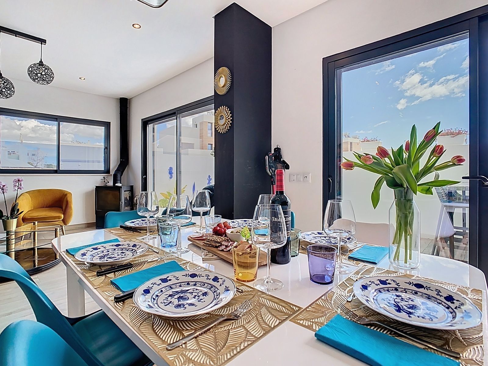 A dining area with a table set for four, large windows, and a view of the sky.
