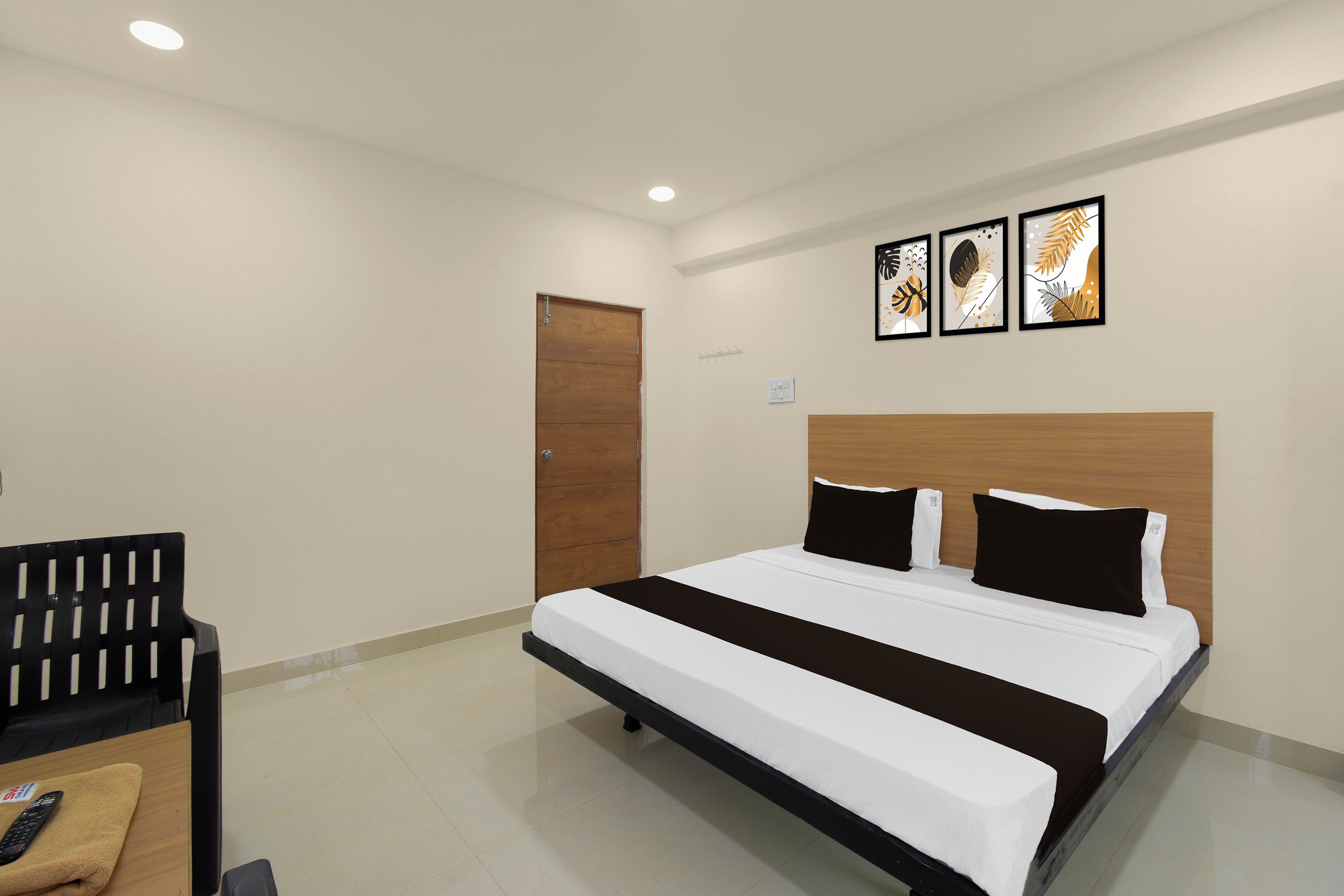 Una habitación de hotel con una cama, una puerta de madera y una lámpara fijada a la pared.