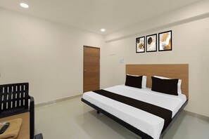 A hotel room with a bed, a wooden door, and a wall-mounted light fixture. - Hotel O SVR Grand Luxury Rooms (Hyderabad)