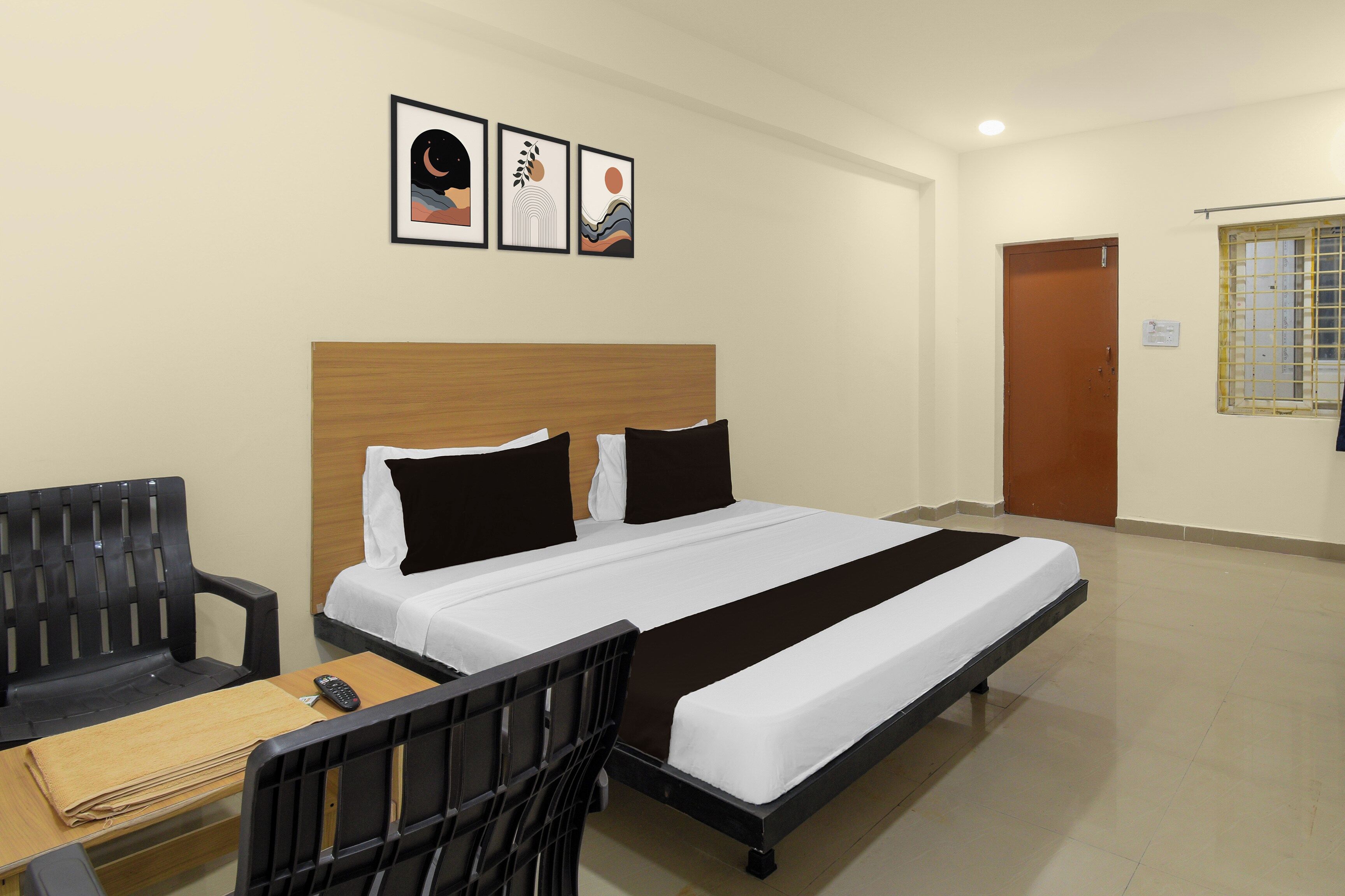 Ein Hotelzimmer mit einem Bett, einem Schreibtisch, einem Stuhl und drei gerahmten Bildern an der Wand.