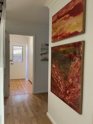 A hallway with wooden flooring, a white door with a window, and two paintings on the wall. - Whisper quiet South Perth oasis near zoo, river, amenities and public transport (South Perth)