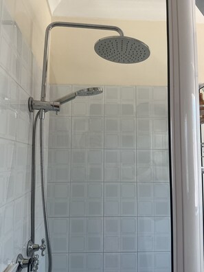 Une douche équipée d’un pommeau de douche à main et d’un robinet mural.