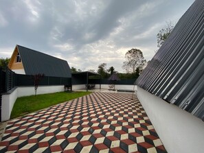 Uma área externa coberta com piso xadrez, churrasqueira e área de estar.