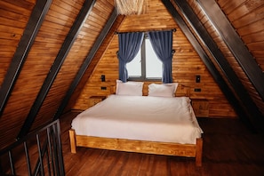 A wooden-paneled room with a bed, two windows with curtains, and a wooden floor.