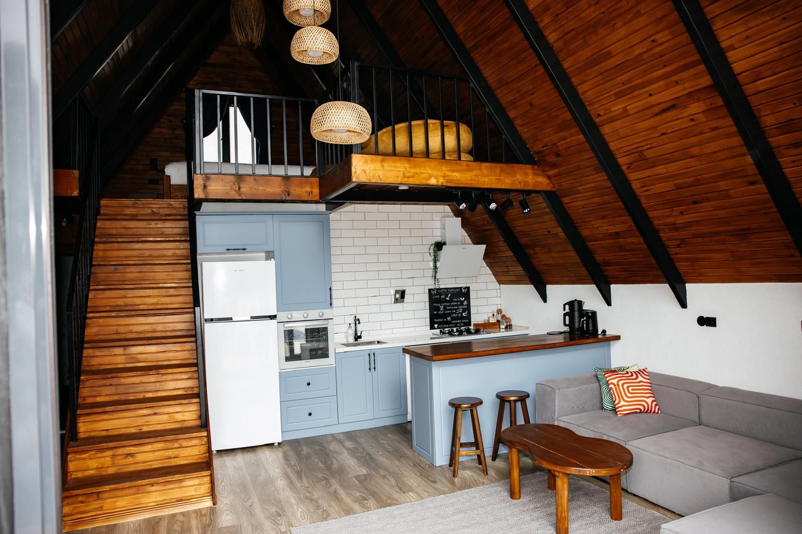 Una cocina compacta con una isla central, un comedor con taburetes y un dormitorio estilo altillo con literas.