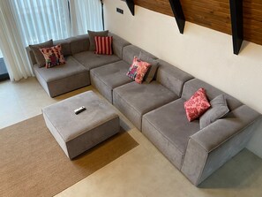 Sala de estar moderna com sofá seccional, apoio para os pés e almofadas decorativas.