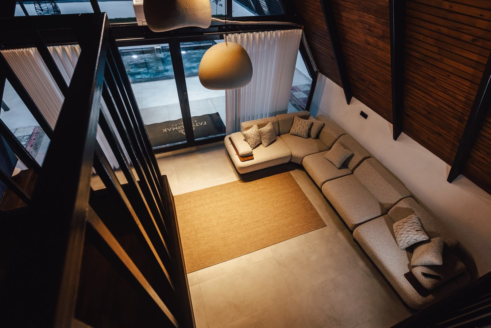 A modern living room with a sectional sofa, a large window, and a view of the outside.