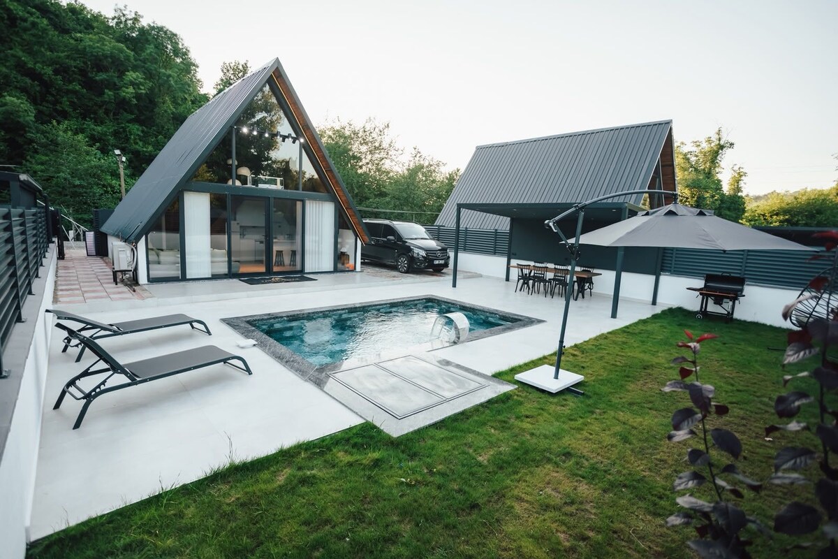 Un área de piscina moderna al aire libre con jacuzzi, sillas de descanso y zona de barbacoa.