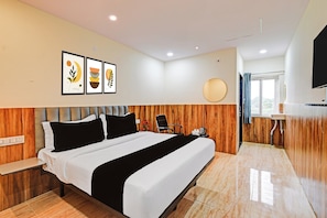A hotel room with a bed, bedside table, a chair, a small table with a kettle, and a TV mounted on the wall. - HOTEL O VEDHANSHI HOTEL BIBINAGAR (Hyderabad)