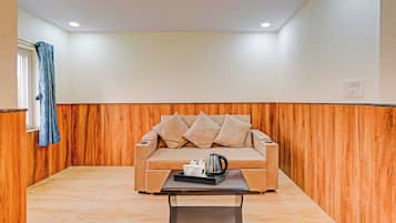Una habitación con un sofá color crema, una mesita de centro y una pared de madera decorativa.