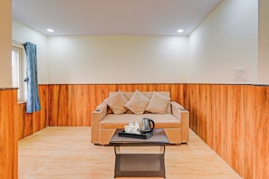 A room with a beige sofa, a coffee table, and a wooden accent wall. - HOTEL O VEDHANSHI HOTEL BIBINAGAR (Hyderabad)