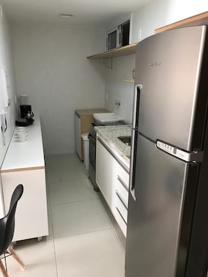Eine kleine Küche mit einem Edelstahlkühlschrank, einer Spüle und einer Kaffeemaschine.