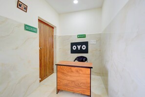 Zona de recepción con mostrador, puerta de madera y cartel con horarios de registro de entrada y salida.