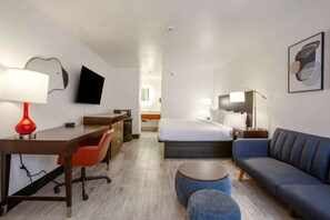 Habitació d'hotel amb un llit, escriptori, cadira, sofà i televisió.