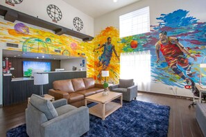 Un hall d’hôtel moderne comprenant un comptoir d’accueil, un espace salon et une grande fresque représentant un joueur de basketball.