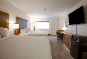 Habitació d'hotel amb dos llits, una taula de treball, televisió i finestra.