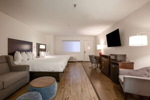 Habitació d'hotel amb un llit, escriptori, televisió, sofà i cadira.