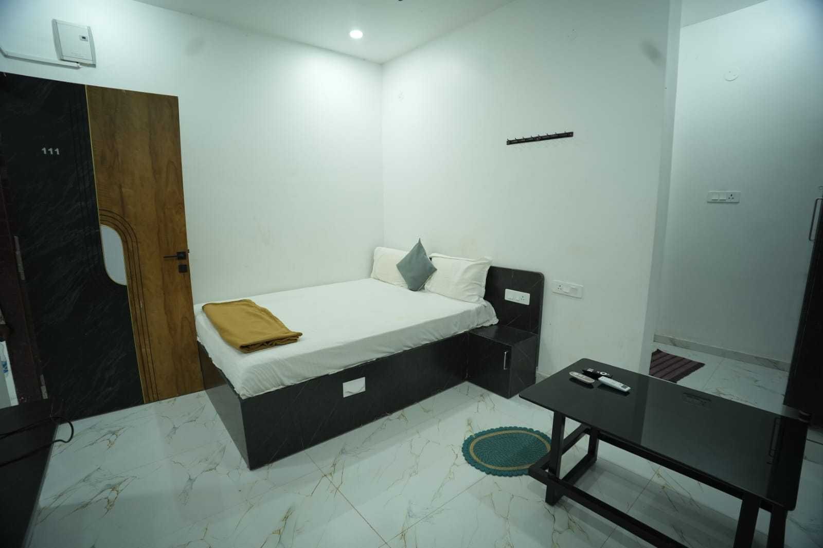 A small, modern room with a bed, a desk, and a door.