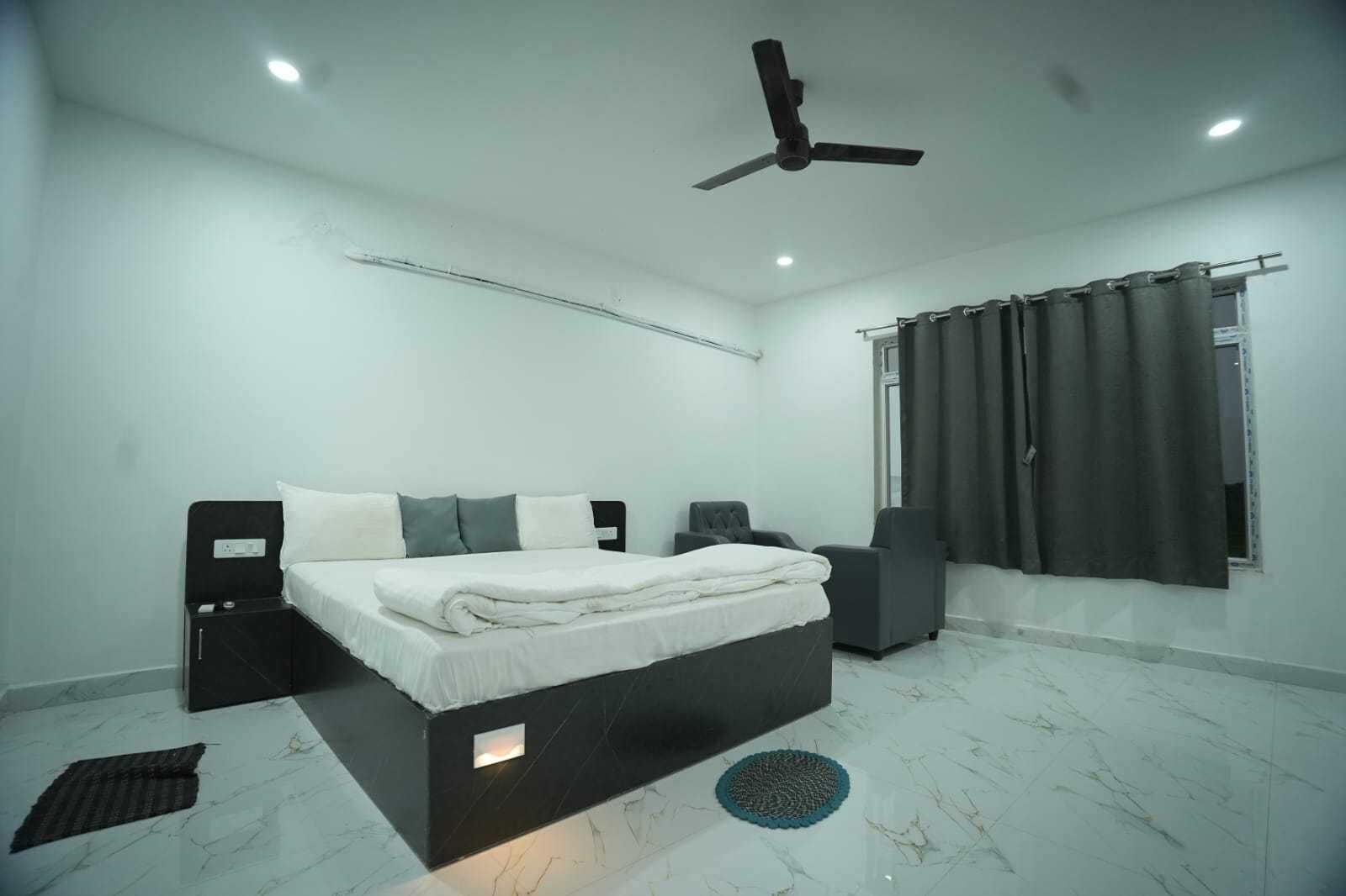 A modern bedroom with a bed, a ceiling fan, a window with curtains, and a marble floor.
