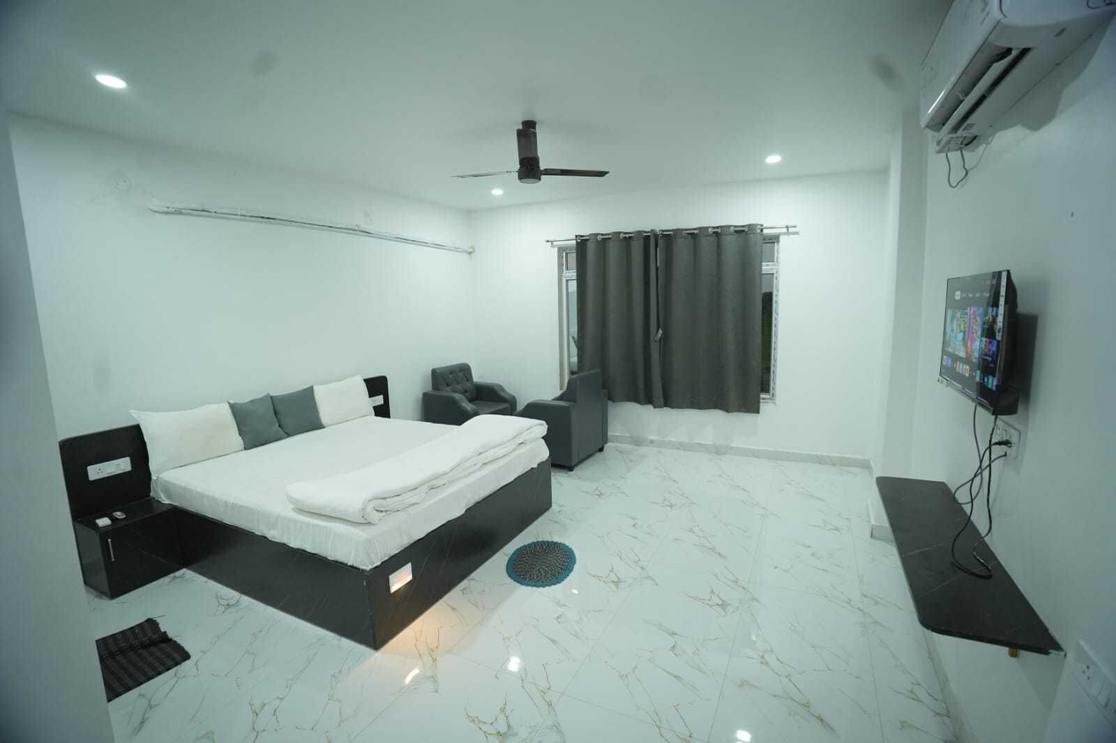 A modern bedroom with a bed, a desk, a chair, a ceiling fan, and an air conditioning unit.