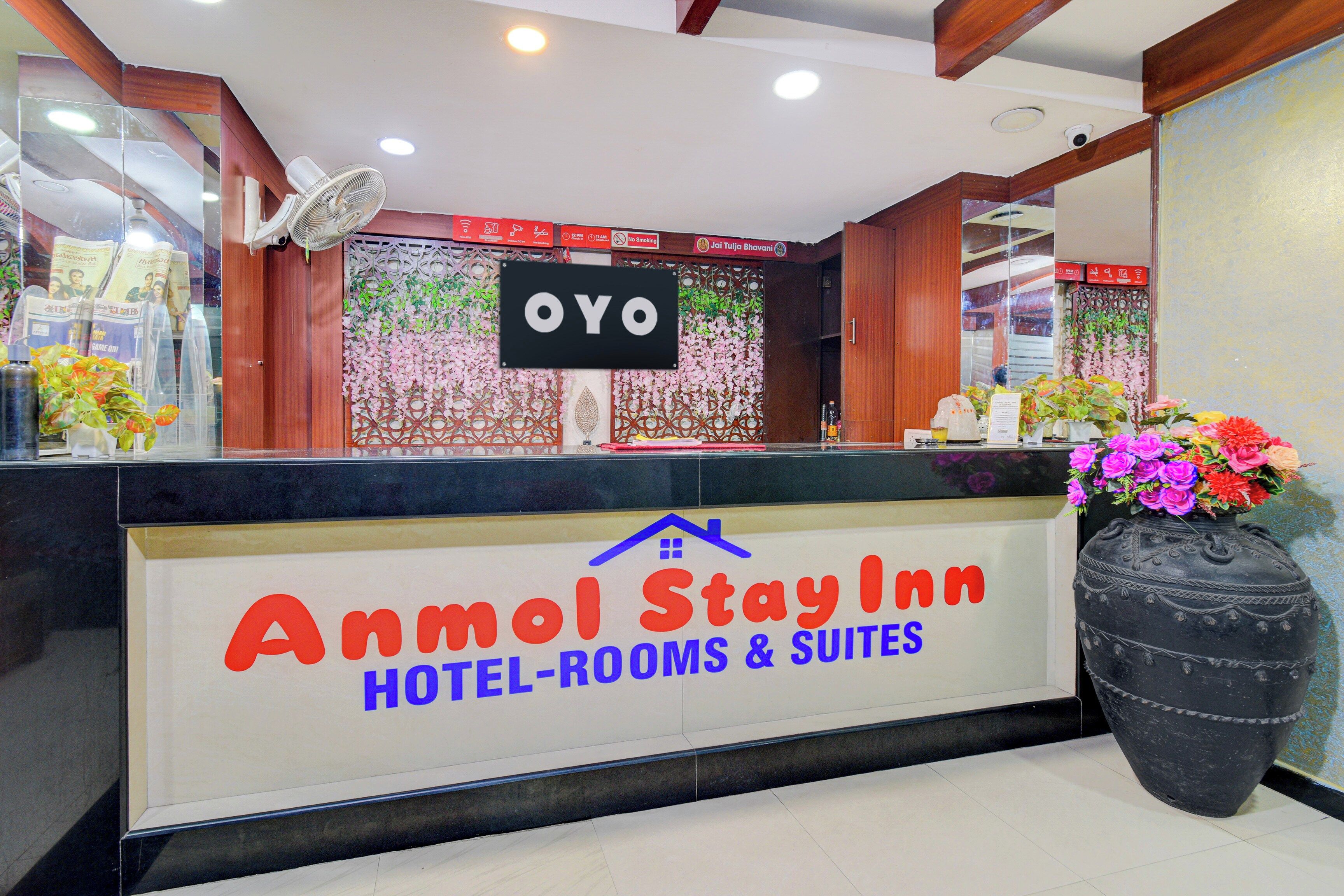 A reception desk with a sign for 'Anmol Stay Inn Hotel-Rooms & Suites'.