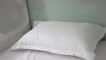 Un lit avec un oreiller blanc et un drap blanc uni.