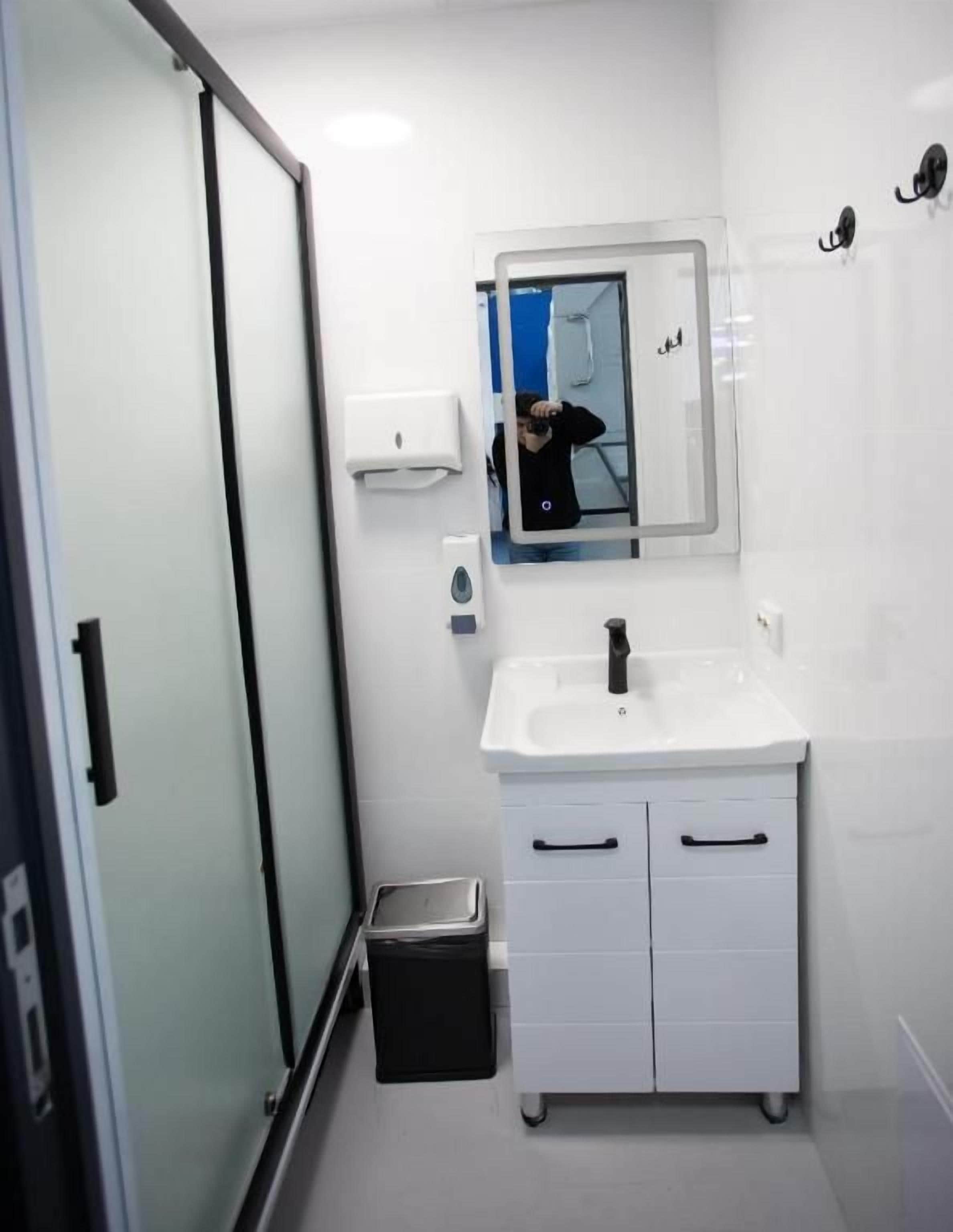 Une salle de bain avec une douche à parois de verre, un lavabo blanc et un miroir.