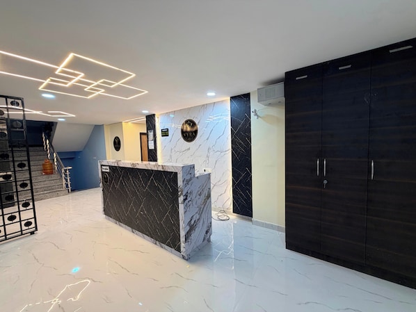 A reception area with a marble counter, dark wood cabinets, and a staircase with a metal railing.