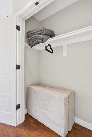A storage closet with a bench, a shelf with folded blankets, and a hanging rack. - 6BR/4BA Duplex | 10 Minutes to Downtown, Lucas Oil & Gainbridge (Indianapolis)