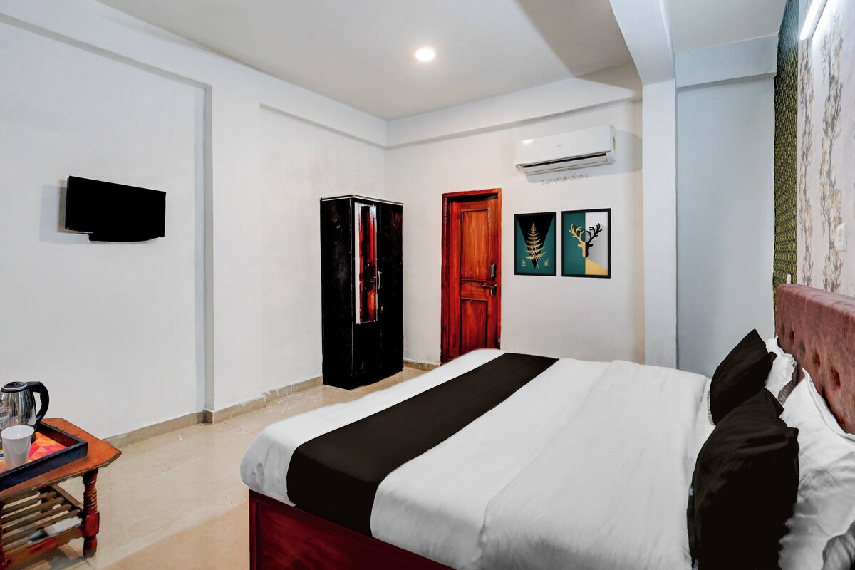 Una habitación de hotel con una cama, un armario, un televisor y una mesita con una tetera.