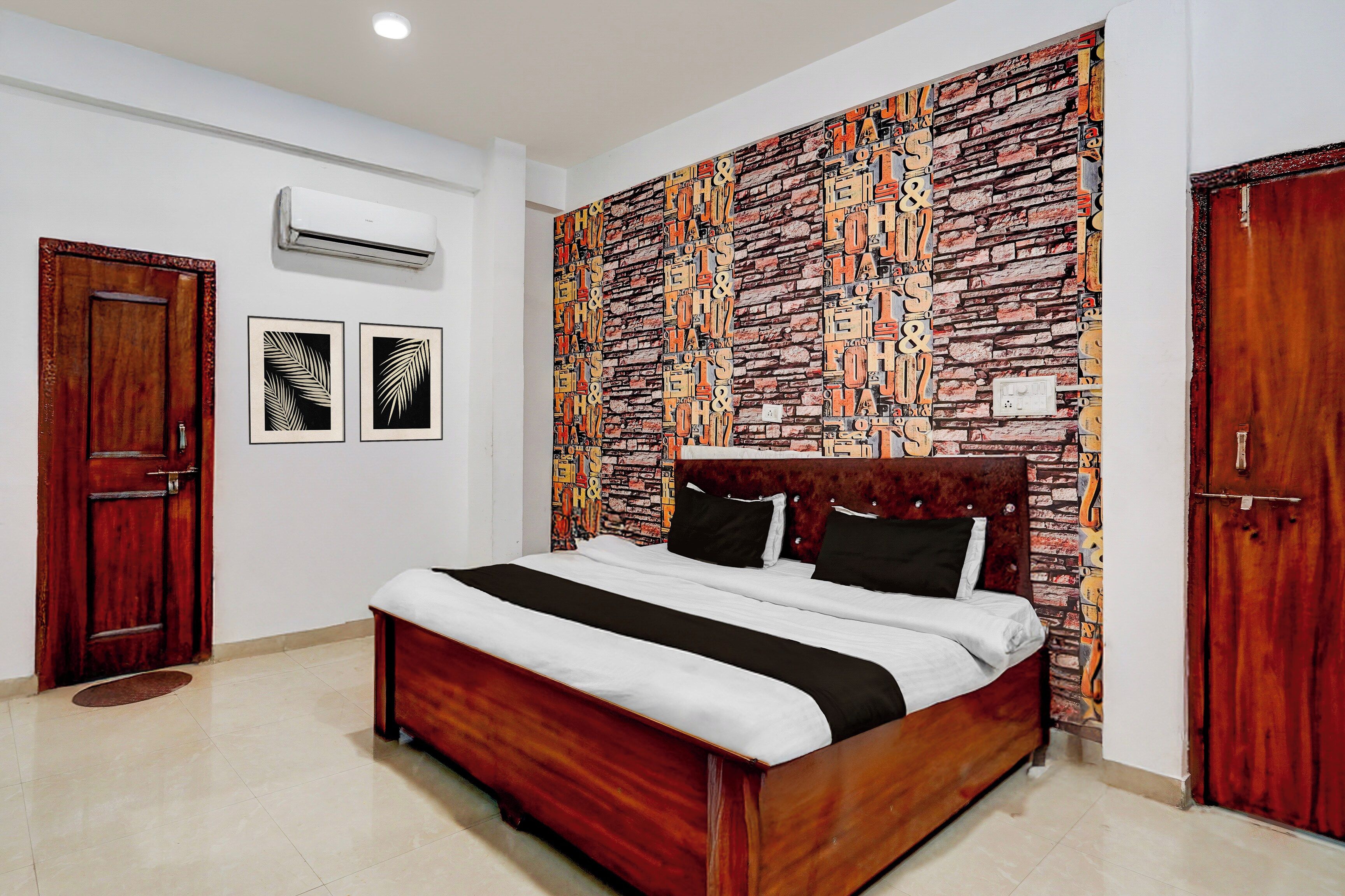 A bedroom with a brick-patterned headboard, a wooden bed, and two framed pictures on the wall.