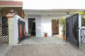 Una entrada protegida por un portón con un camino de concreto que lleva a la entrada de un edificio.