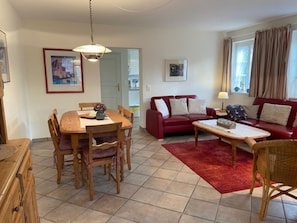 A living room with a dining table, red sofa, and a red rug. - Strandstrasse 28, Half of the House on the Left (Nieblum)