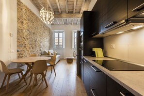 A modern kitchen with dark cabinetry, a built-in oven, and a yellow coffee machine. - Colonna Suite by MMega Homes and Villas (Florence)