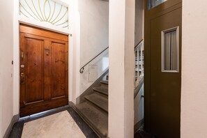 A wooden door with a brass handle, a carpeted staircase, and a metal handrail. - Colonna Suite by MMega Homes and Villas (Florence)