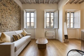 Une pièce avec un mur en pierre, un canapé, un plancher en bois et un radiateur.