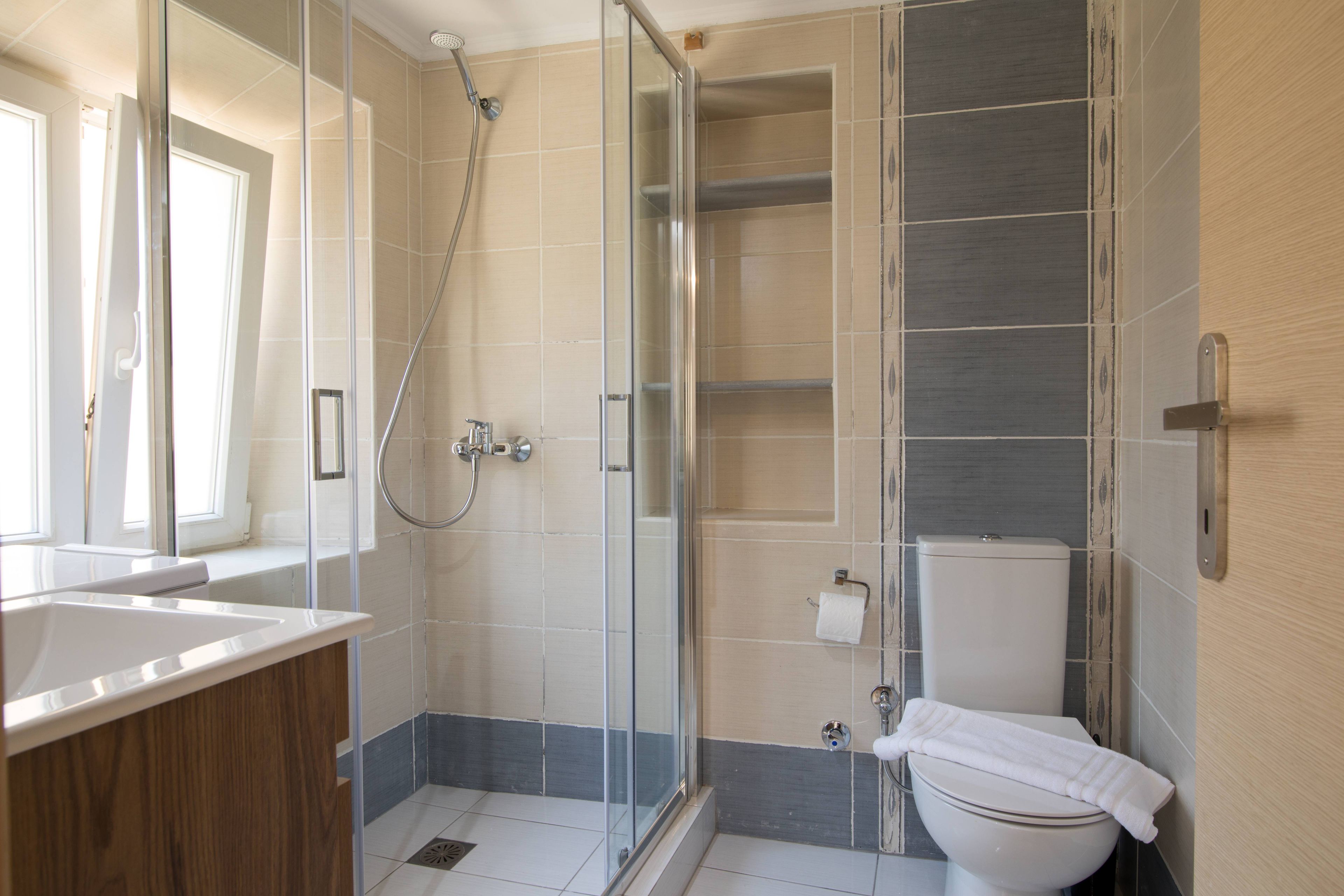 A modern bathroom with a glass shower enclosure, a white toilet, and a wooden vanity.