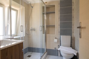 A modern bathroom with a glass shower enclosure, a white toilet, and a wooden vanity. - Alto Residences by CorfuEscapes  (Corfu)
