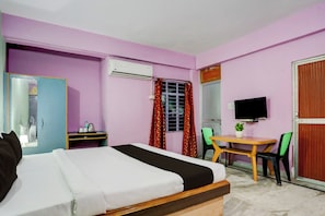 A hotel room with a bed, a desk, a chair, an air conditioning unit, a television, and a window with curtains. - Super Hotel O Anjanpeer Post Office (Hajipur)