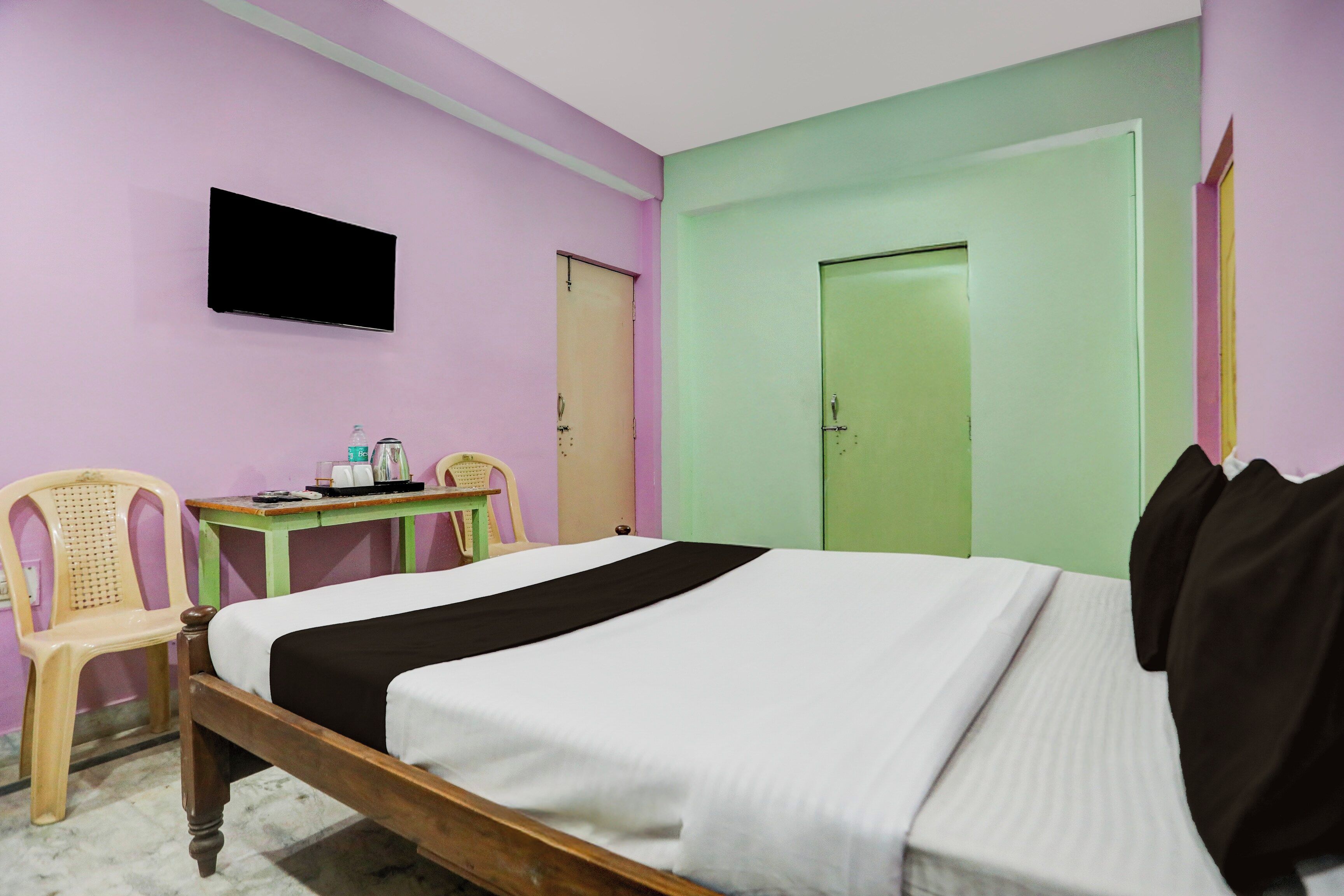 A room with a bed, a desk, a chair, a television, and a door.