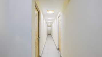 Um corredor estreito e bem iluminado, com portas em ambos os lados, que dá acesso a quartos.